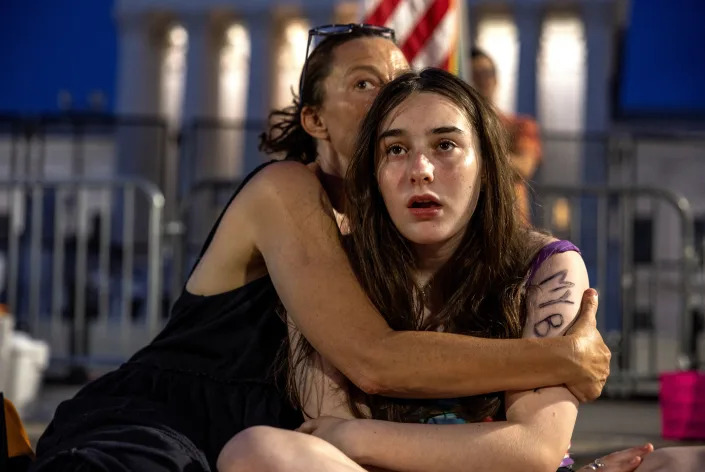 Lisa Turner holds her teenage daughter Lucy Kramer during a candlelight vigil outside the Supreme Court on Sunday night