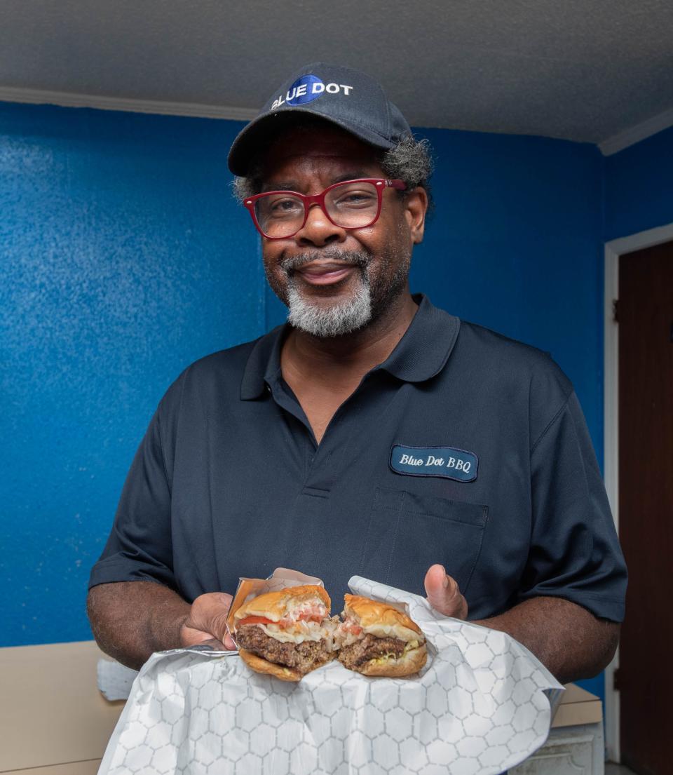 Owner J. Byron Long holds cheeseburger at the Blue Dot restaurant in the Belmont-DeVilliers neighborhood in downtown Pensacola on Wednesday, Nov. 16, 2022.