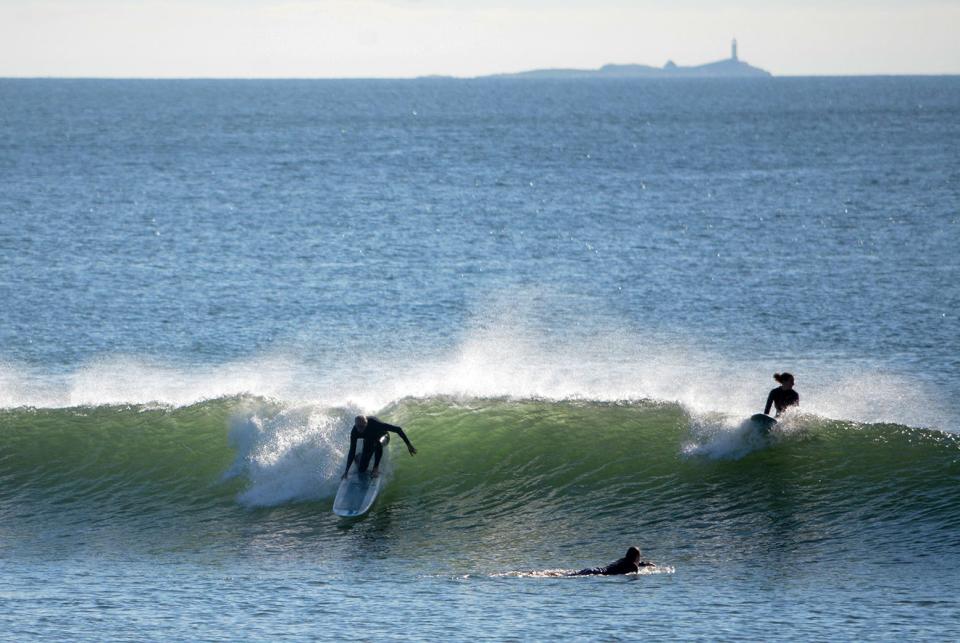 Three surfers enjoy the waves brought by Hurricane Lee Thursday at Fox Hill in Rye.