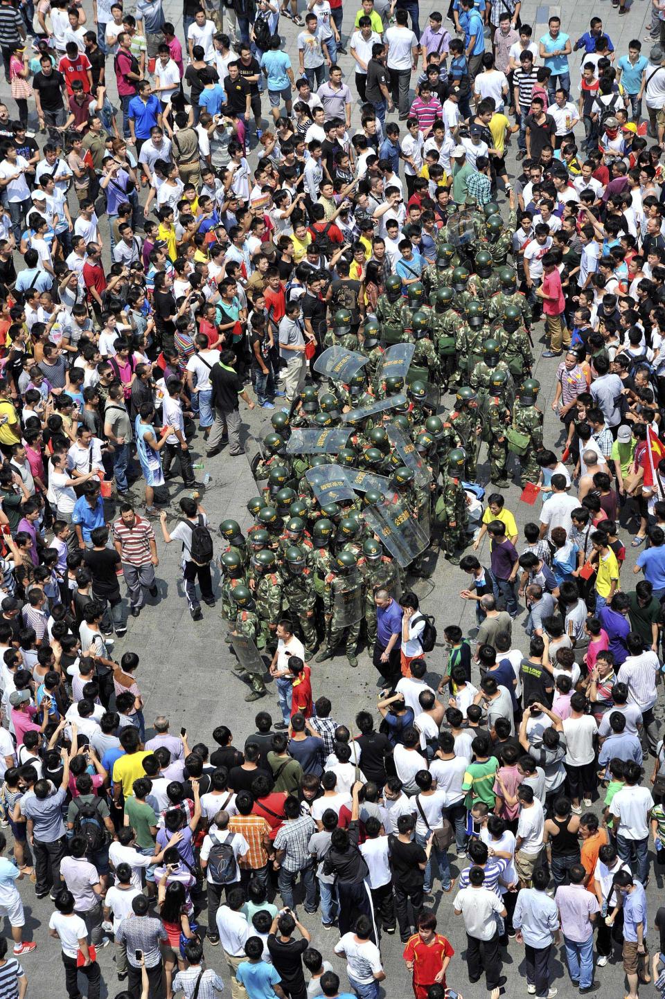 A group of paramilitary policemen are surrounded by anti-Japan protesters outside Shenzhen city's Communist Party headquarters, in southern China's Guangdong province, Sunday, Sept. 16, 2012. Protesters in China continued another day of demonstrations against Japan Sunday, after protests over disputed islands spread across numerous cities and at times turned violent. (AP Photo) CHINA OUT