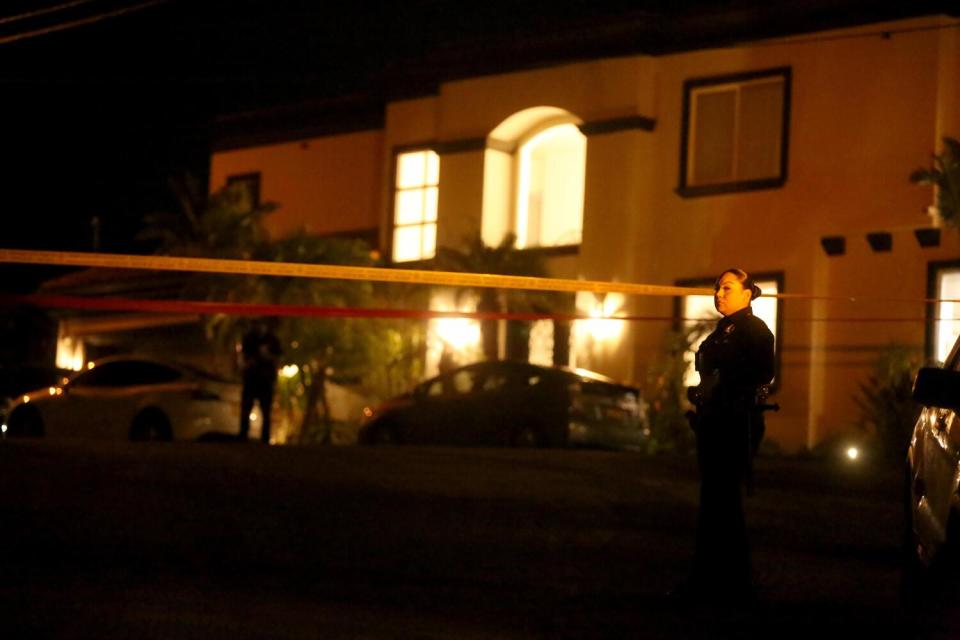 Police monitor the scene near a home at night.