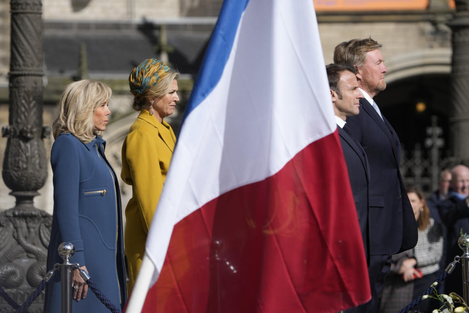 French President Emmanuel Macron, second left, his wife Brigitte Macron, right, Dutch King Willem-Alexander, right, and Queen Maxima listen to national anthems outside the royal palace on Dam square in Amsterdam, Netherlands, Tuesday, April 11, 2023. French President Emmanuel Macron begins a two-day state visit to the Netherlands on Tuesday and is making a speech on his vision for the future of Europe. (AP Photo/Peter Dejong)