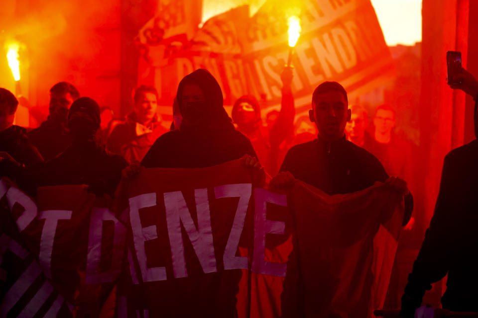 Demonstrators light flares during a demonstration against measures to battle the coronavirus pandemic in Vienna, Austria, Saturday, Nov. 20, 2021. Thousands of protesters are expected to gather in Vienna after the Austrian government announced a nationwide lockdown to contain the quickly rising coronavirus infections in the country. Banner reads: Great exchange, Great Reset, Stop the globalist filth'. (AP Photo/Florian Schroetter)