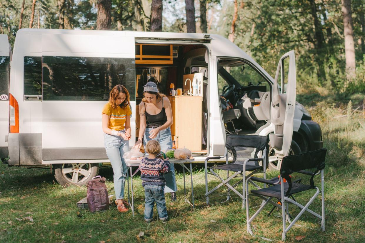 Young Caucasian women and little boy   cooking burger on grill in forest