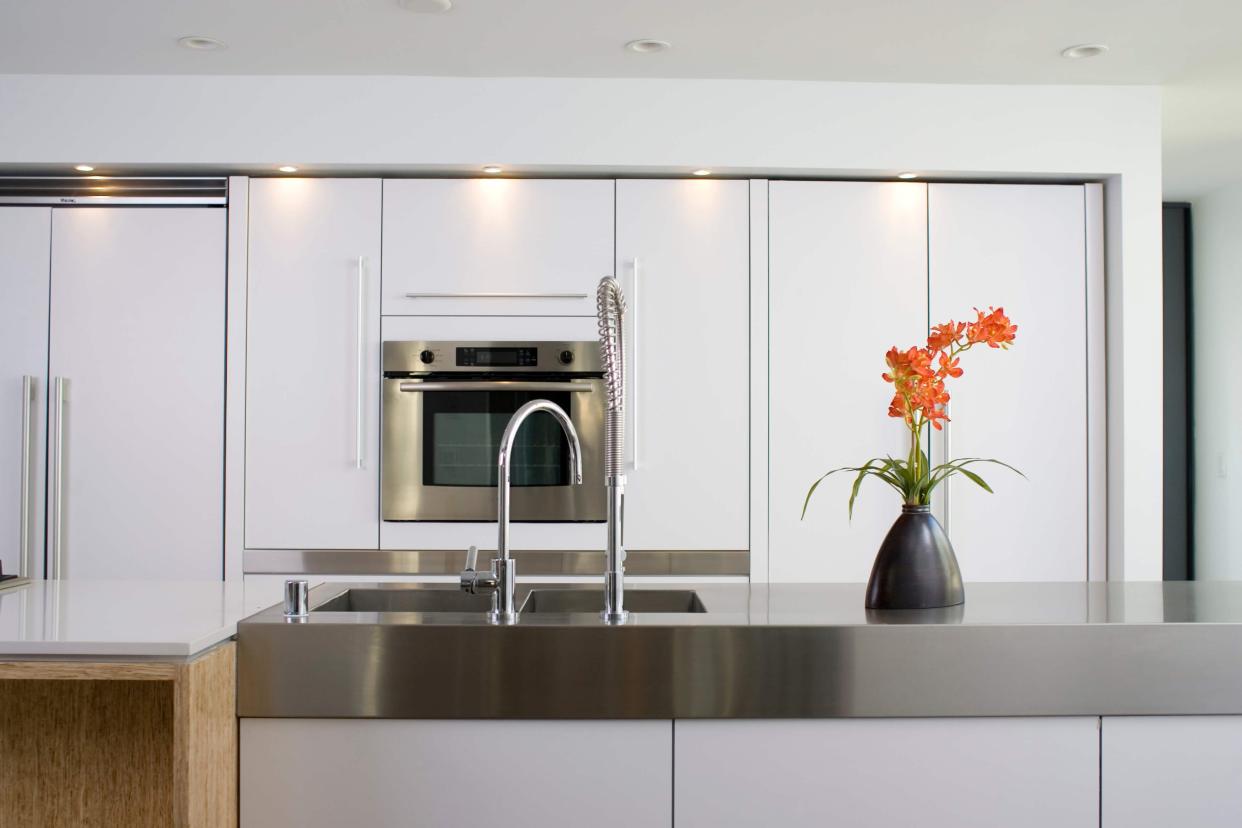 Modern white kitchen with stainless steel counter and oven