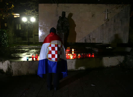 A Bosnian Croat, wrapped in a flag of unrecognised wartime Croat statelet, prays for the convicted general Slobodan Praljak who killed himself seconds after the verdict in the U.N. war crimes tribunal in The Hague, in Mostar, Bosnia and Herzegovina November 29, 2017. REUTERS/Dado Ruvic