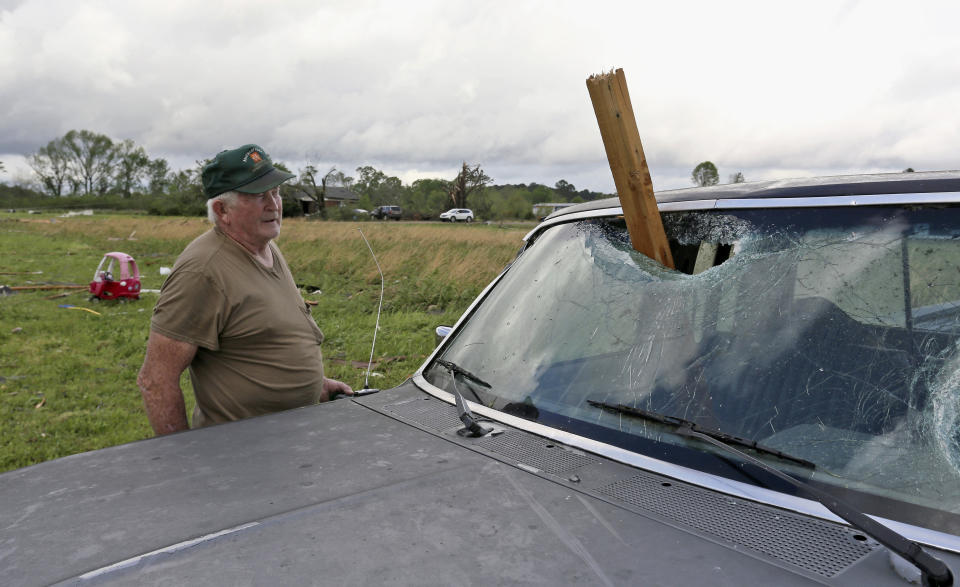 A man looks at a piece of wood that was blown through the windshield of his daughters truck in Hamilton, Miss., after a storm moved through the area Sunday, April 14, 2019. (AP Photo/Jim Lytle)