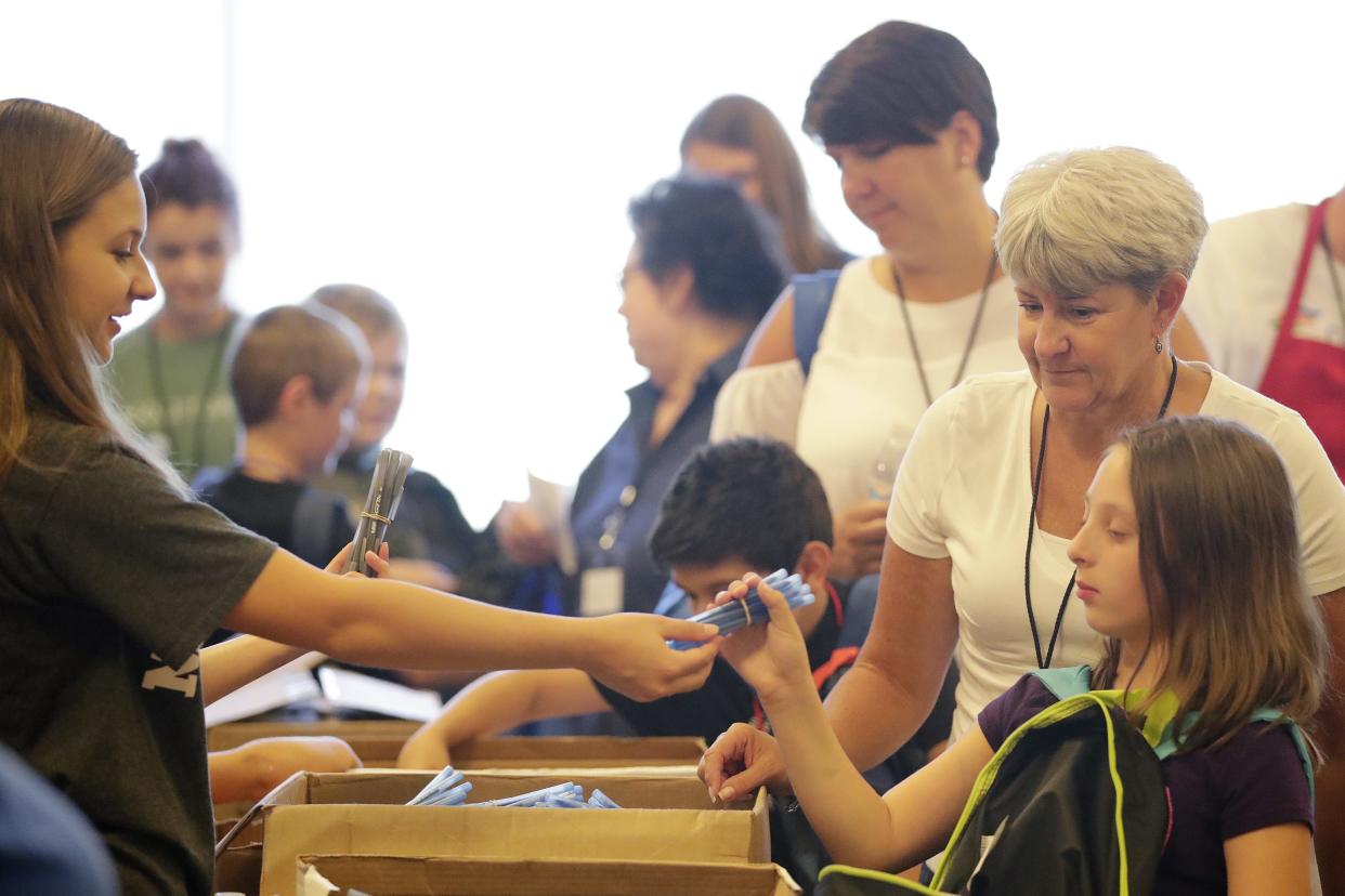 Volunteer Lainey Simonson hands out pens to children at the Back-to-School Store at University of Wisconsin-Green Bay in August 2018. The two-day event returns to the UWGB campus Tuesday and Wednesday.