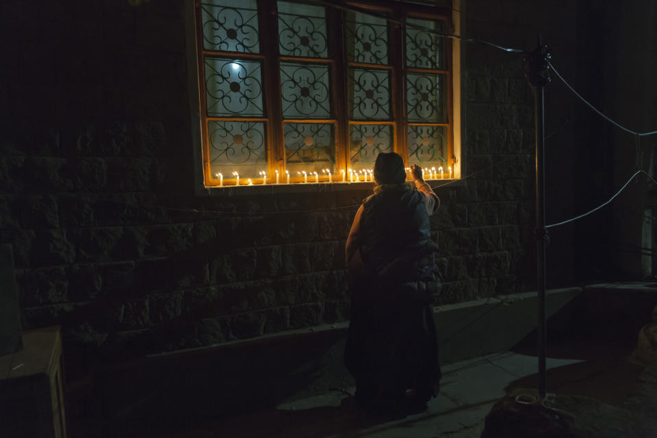 In this Sunday, Dec. 2, 2018, file photo, an exile Tibetan lights candles in front of her house as Tibetans mark the death anniversary of Tsongkhapa, in Dharmsala, India. Tsongkhapa is the founder of the Gelug school of Tibetan Buddhism to which the Dalai Lama belongs. (AP Photo /Ashwini Bhatia, File)