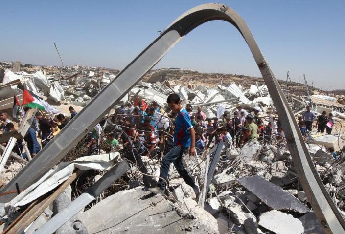 Palestinian students take part in a demonstration amidst the ruins of an Islamic Society dairy factory which was demolished by Israeli authorities earlier this week in the West Bank city of Hebron, on September 4, 2014 (AFP Photo/Hazem Bader)