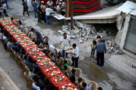 People gather for Iftar (breaking fast), organised by Adaleh Foundation, amidst damaged buildings during the holy month of Ramadan in the rebel-held besieged town of Douma to the east of Damascus, Syria, June 18, 2017. REUTERS/Bassam Khabieh/File Photo