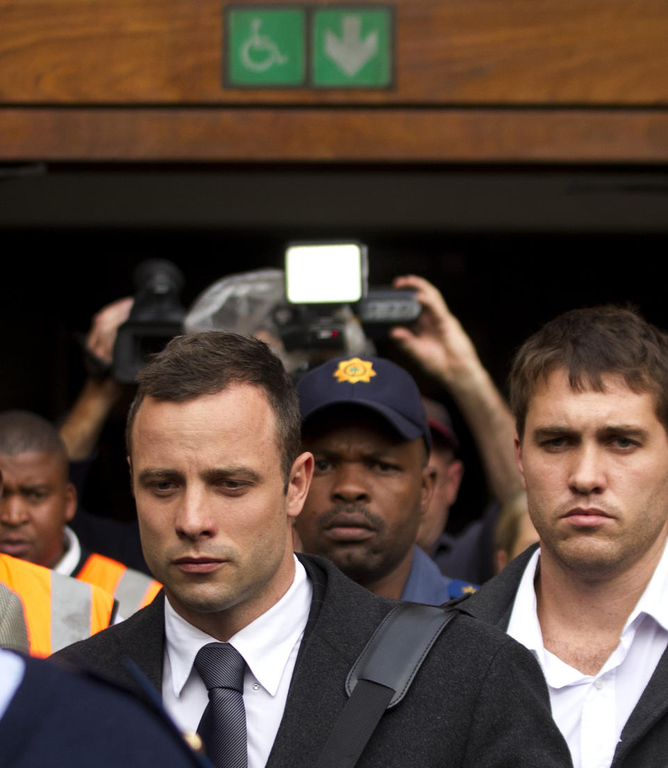 Oscar Pistorius, left, with unidentified man leaves the high court in Pretoria, South Africa, Tuesday, March 11, 2014. Pistorius is charged with murder for the shooting death of his girlfriend, Reeva Steenkamp, on Valentines Day in 2013. (AP Photo/Themba Hadebe)