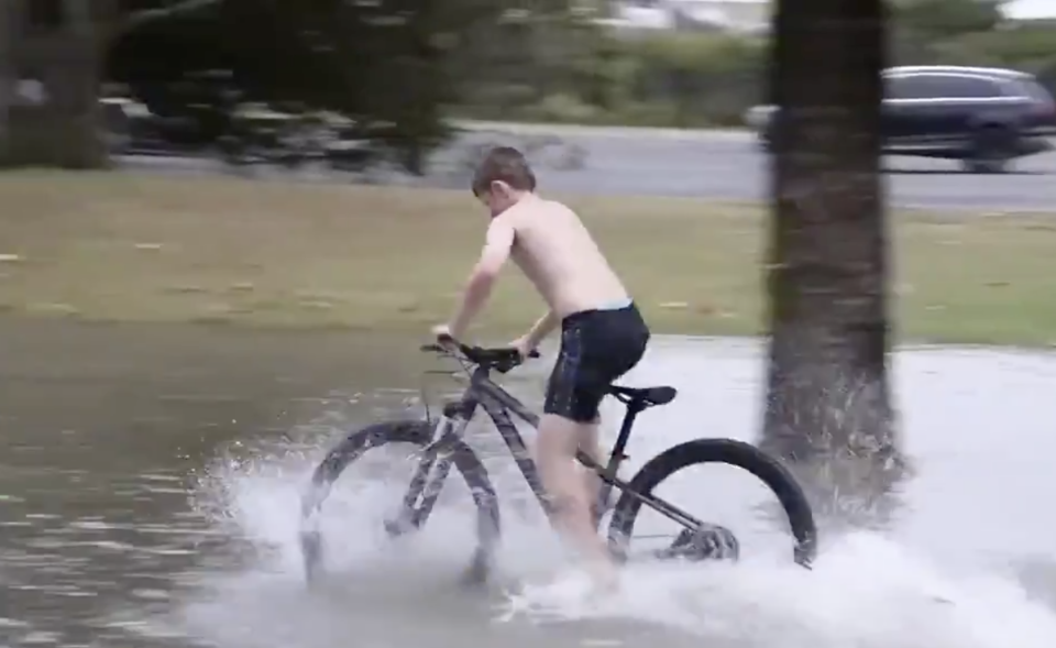 A boy rides a bike through floodwaters in South East Queensland.