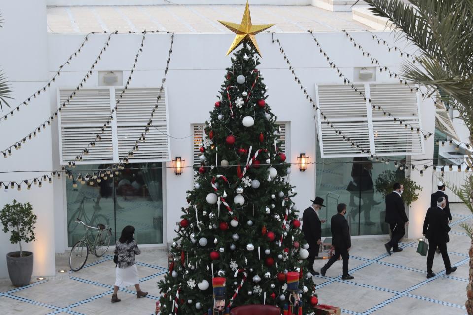 A rabbi and other guests pass a Christmas tree to take part in an Israeli wedding ceremoney in Dubai, United Arab Emirates, Thursday, Dec. 17, 2020. For the past month, Israelis long accustomed to traveling incognito, if at all, to Arab countries, have made themselves at home in the UAE’s commercial hub. (AP Photo/Kamran Jebreili)