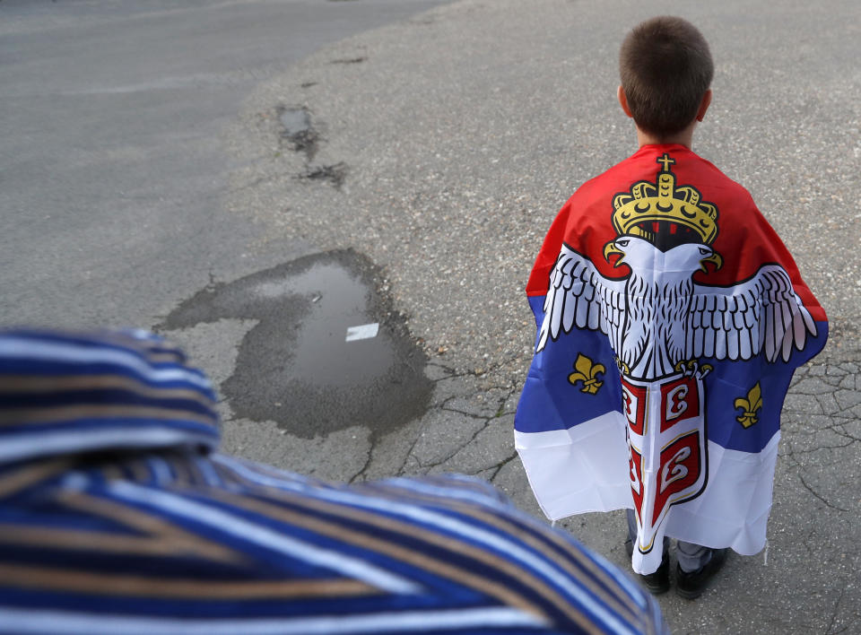 A boy with an old Montenegro flag attends during a protest after arrest of the Serbian Orthodox Church priests in Montenegro, in Belgrade, Serbia, Thursday, May 14, 2020. Montenegrin police said Thursday they have detained around 60 people following clashes at protests demanding the release of eight Serbian Orthodox Church priests jailed for leading a religious procession despite a ban on gatherings related to the new coronavirus outbreak. (AP Photo/Darko Vojinovic)
