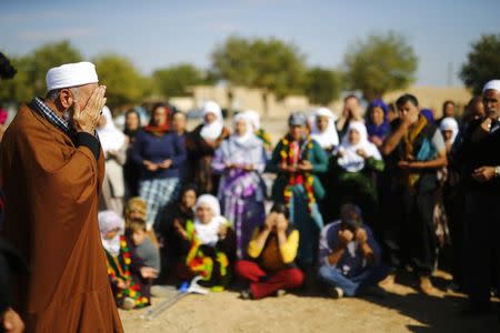 Kurdish People's Protection Unit (YPG) supporters watch as an imam prays, in Telcarut village near the Mursitpinar border crossing, on the Turkish-Syrian border in the southeastern town of Suruc in Sanliurfa province October 25, 2014. REUTERS/Kai Pfaffenbach