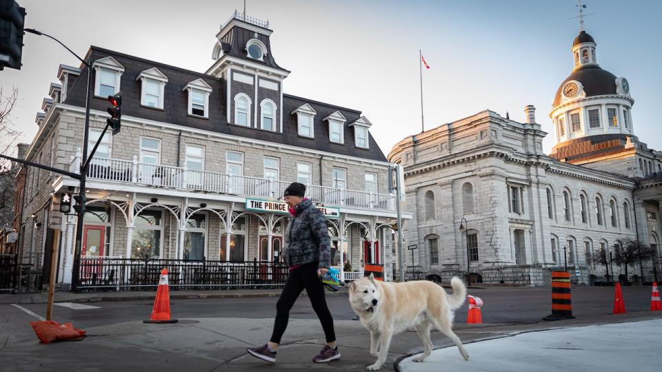 A woman walks with her dog past the Prince George Hotel and City Hall in downtown Kingston, Ont., April 21, 2022.