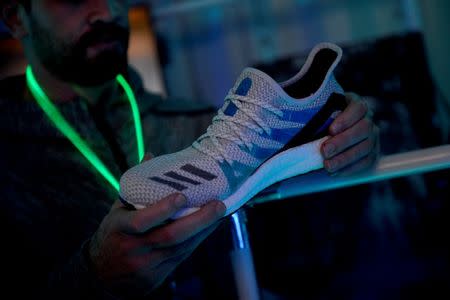 A staff member displays a shoe, at the launch of Adidas' new shoe line, made in a factory largely operated by robots, in London, Britain October 19, 2017. REUTERS/Mary Turner