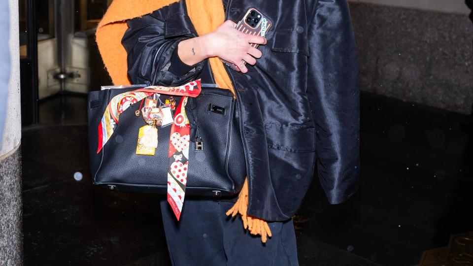 Dua Lipa is seen in NYC wearing a black sweat suit and orange scarf 