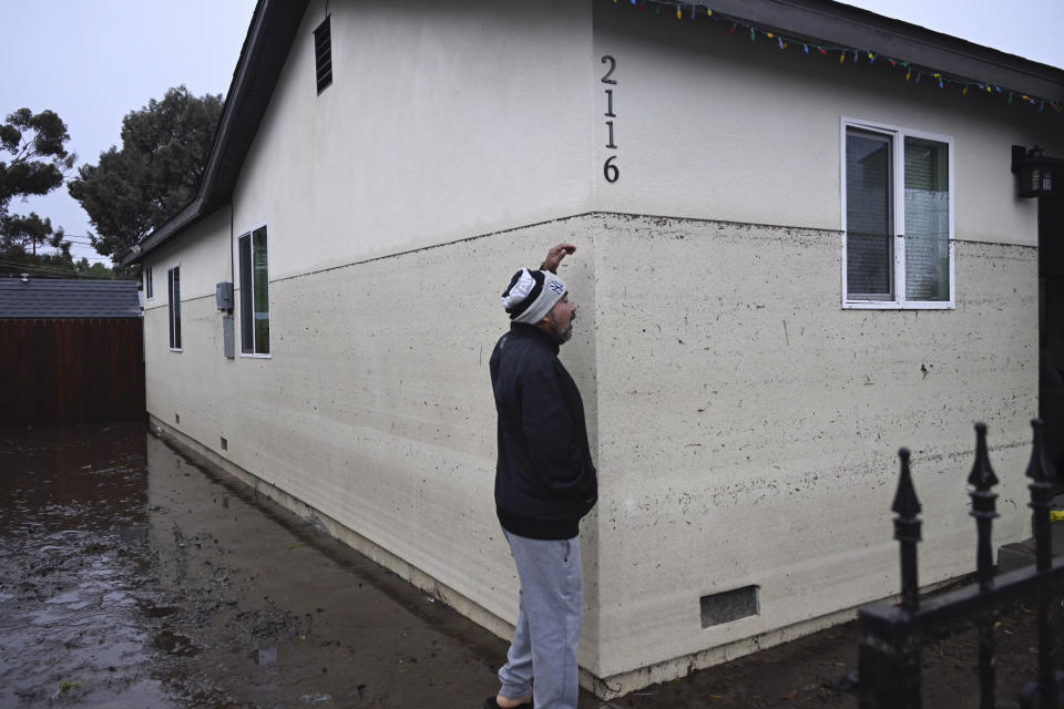 Juan Gonzales gestures to the waterline of a flooded home during a rain storm Monday, Jan. 22, 2024, in San Diego. (AP Photo/Denis Poroy)