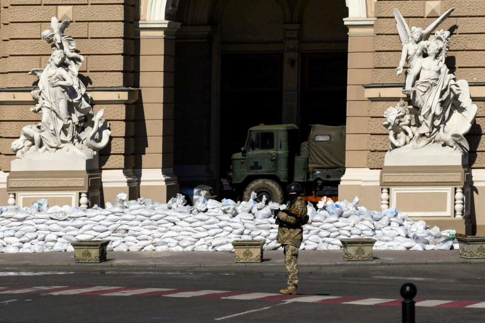 A Ukrainian soldier stands guard near sandbag barricades outside the Odesa Opera and Ballet Theater.