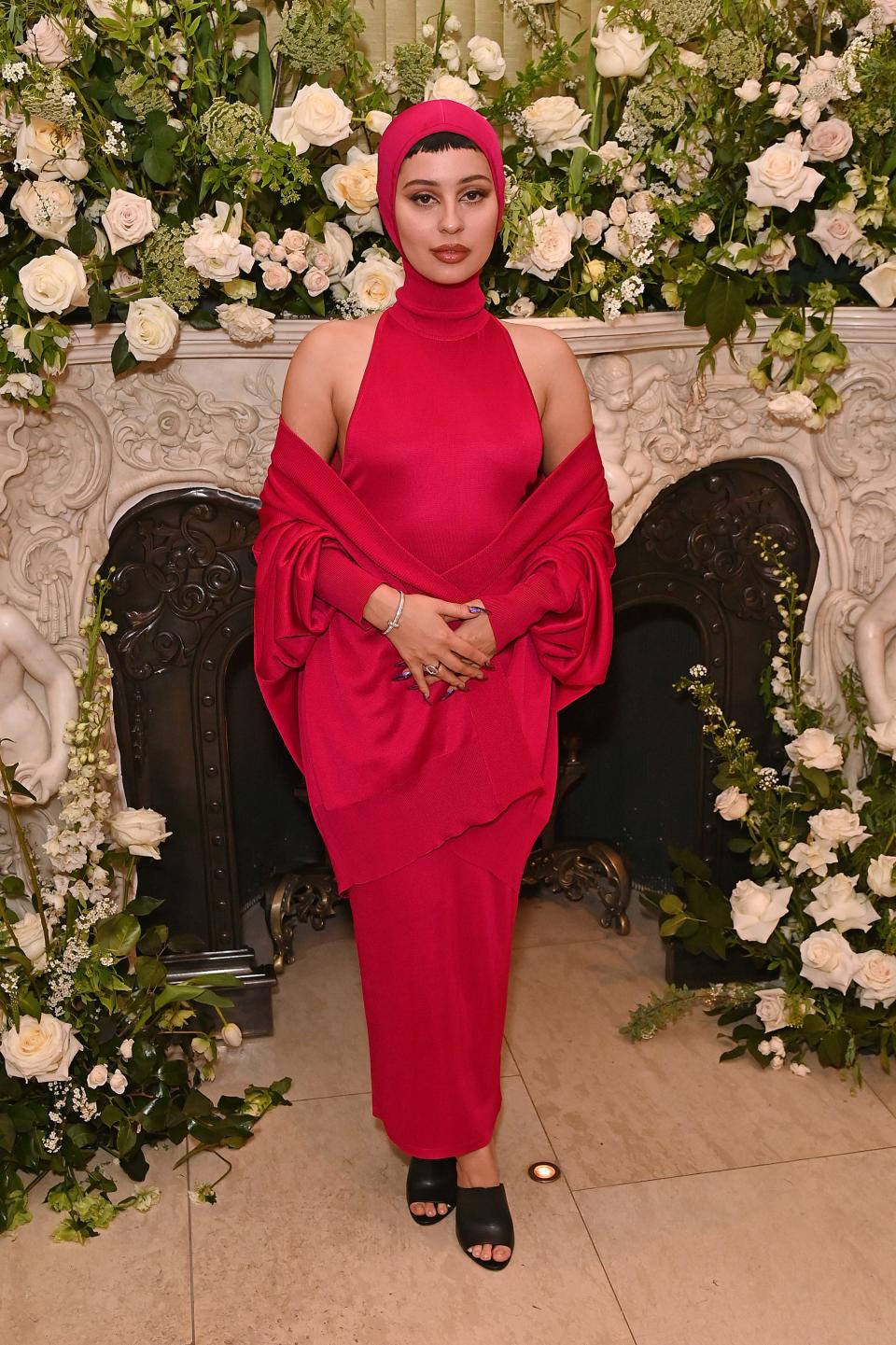 Alexa in a red halter dress with a matching red head covering and arm shawl.