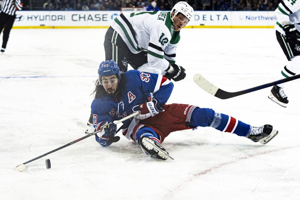 New York Rangers center Mika Zibanejad (93) makes a play on the puck after being tripped by Dallas Stars left wing Jamie Benn during the second period of an NHL hockey game on Tuesday, Feb. 20, 2024 in New York. (AP Photo/Peter K. Afriyie)