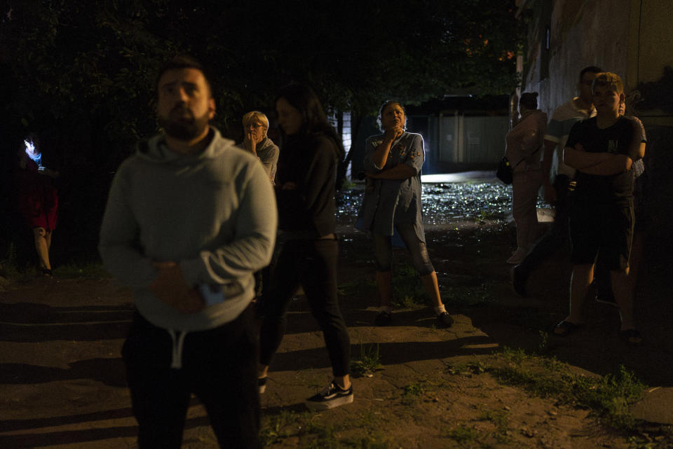 Residents stand outside an apartment building damaged in Russia's air attacks in Kyiv, Ukraine, Thursday, July 13, 2023. (AP Photo/Jae C. Hong)