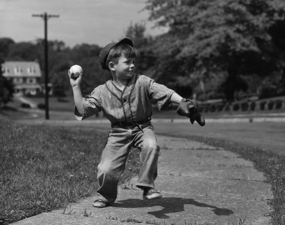 Circa 1955:  A young boy throwing a baseball on a sidewalk.  (Photo by Lambert/Getty Images)