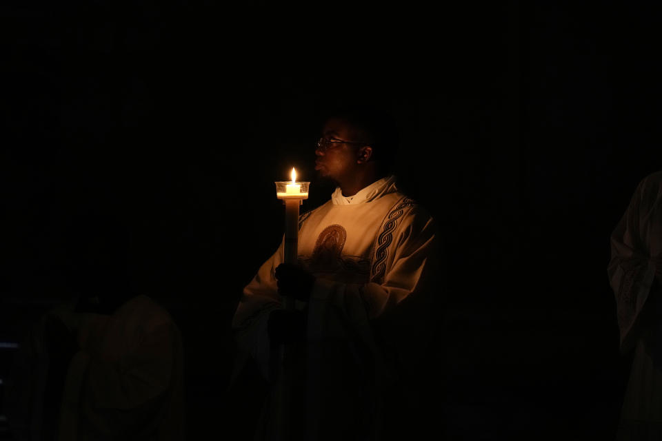 A priest holds candle over the Easter vigil celebration in St. Peter's Basilica at the Vatican, Saturday, March 30, 2024. (AP Photo/Alessandra Tarantino)