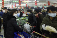 People wearing masks buy foods at a supermarket in Hangzhou in east China's Zhejiang province, Saturday, Feb. 8, 2020. China's communist leaders are striving to keep food flowing to crowded cities despite anti-disease controls, to quell fears of possible shortages and stave off price spikes from panic buying after most access to Wuhan was cut off Jan. 23. Food stocks in supermarkets ran low shortly after Beijing imposed travel curbs and extended the Lunar New Year holiday to keep factories, offices and other businesses closed and the public at home, attempting to prevent the virus from spreading. (Chinatopix via AP)