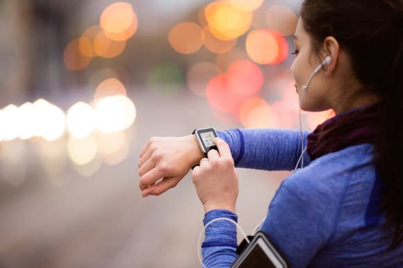 A young woman selects music on her smart watch.