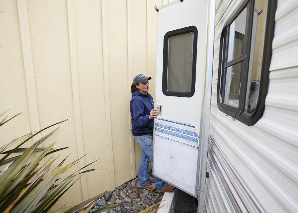 Melynda Small walks into a the trailer she is living in in the parking lot of a Comfort Inn in Lincoln City, Ore., on Thursday, May. 13, 2020. Small has dedicated her time to helping the small Oregon coast town of Otis recover from the devastating fire that destroyed 293 homes. She is living in the trailer while her four children live in the hotel. Experts say the 2020 wildfire season in Oregon was a taste of what lies ahead as climate change makes blazes more likely and more destructive even in wetter, cooler climates like the Pacific Northwest. (AP Photo/Craig Mitchelldyer)