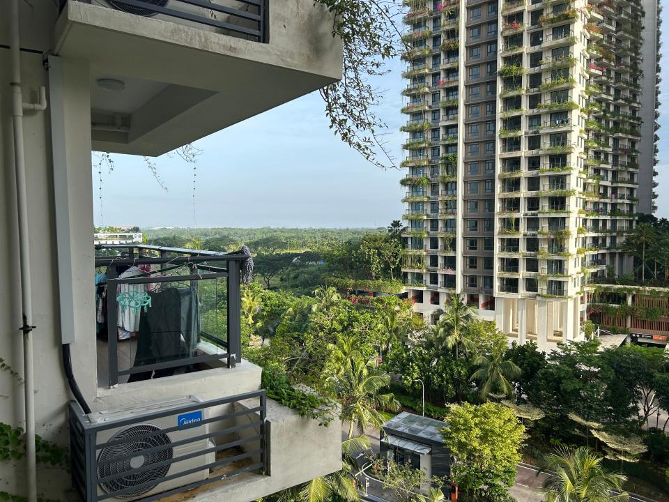 A balcony overlooking a block of apartments covered in foliage.