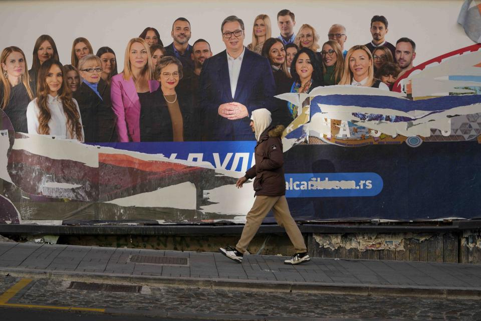 A man walks past a damaged pre-election billboard showing Serbian President Aleksandar Vucic with members of his ruling Serbian Progressive Party in Belgrade, Serbia, Monday, Dec. 18, 2023. An early official vote count of Serbia's weekend election on Monday confirmed victory for the ruling populist party in a parliamentary vote in the Balkan country, but political tensions rose over reported irregularities in the capital, Belgrade. (AP Photo/Darko Vojinovic)