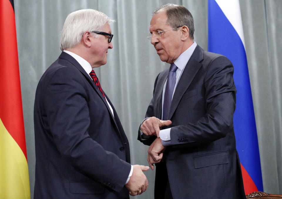 Russian Foreign Minister Sergey Lavrov, right, points at his wristwatch while speaking to his German counterpart Frank-Walter Steinmeier as they leave after a news conference in Moscow, Russia, Friday, Feb. 14, 2014. (AP Photo/Alexander Zemlianichenko)