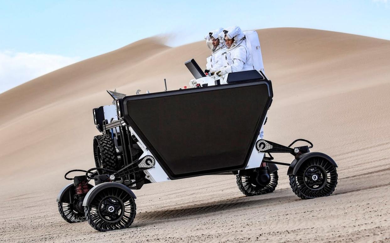 A prototype for a lunar rover, being tested in Death Valley National Park, with two 'astronauts' standing on the back