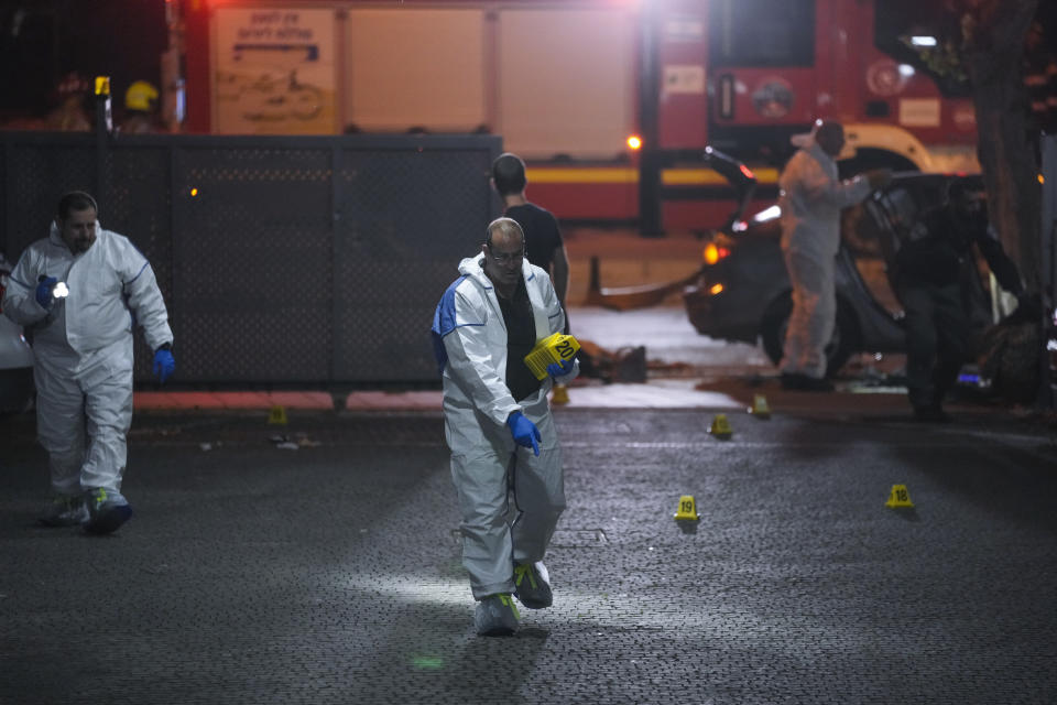 Israeli police inspect the scene of a shooting attack In Hadera, Israel, Sunday, March 27, 2022. A pair of gunmen killed two people and wounded four others in a shooting spree in central Israel before they were killed by police, according to police and medical officials. The identity of the gunmen was not immediately known, but police called them "terrorists," the term usually used for Arab assailants. (AP Photo/Ariel Schalit)