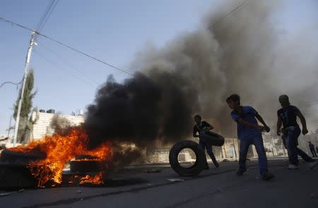 Palestinians burn tires following a protest against the Israeli police raid on Jerusalem's al-Aqsa mosque on Tuesday, in the occupied West Bank city of Hebron September 18, 2015. REUTERS/Mussa Qawasma