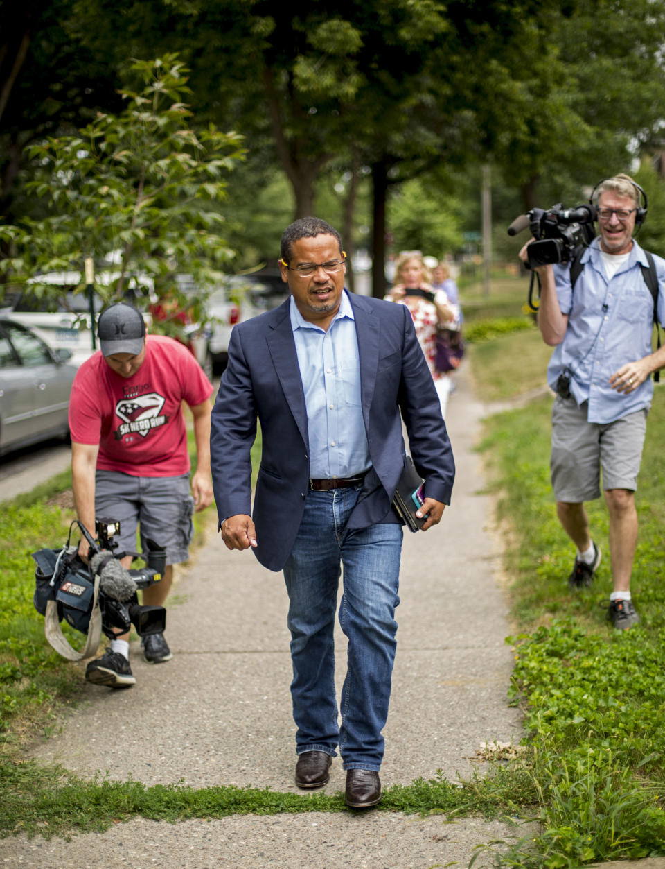 Rep. Keith Ellison is flanked by members of the media as he walks down N. James St. to start his door knocking campaign, Friday, Aug. 17, 2017 in Minneapolis. Minnesota Rep. Keith Ellison said Friday he won't abandon his campaign for attorney general amid allegations that he once physically abused an ex-girlfriend and said if she claims to have a video of the incident she should produce it. (Alex Kormann/Star Tribune via AP)