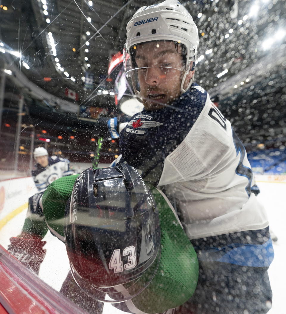 Winnipeg Jets center Pierre-Luc Dubois, top, puts Vancouver Canucks defenseman Quinn Hughes (43) into the boards during second-period NHL hockey game action in Vancouver, British Columbia, Sunday, Feb. 21, 2021. (Jonathan Hayward/The Canadian Press via AP)