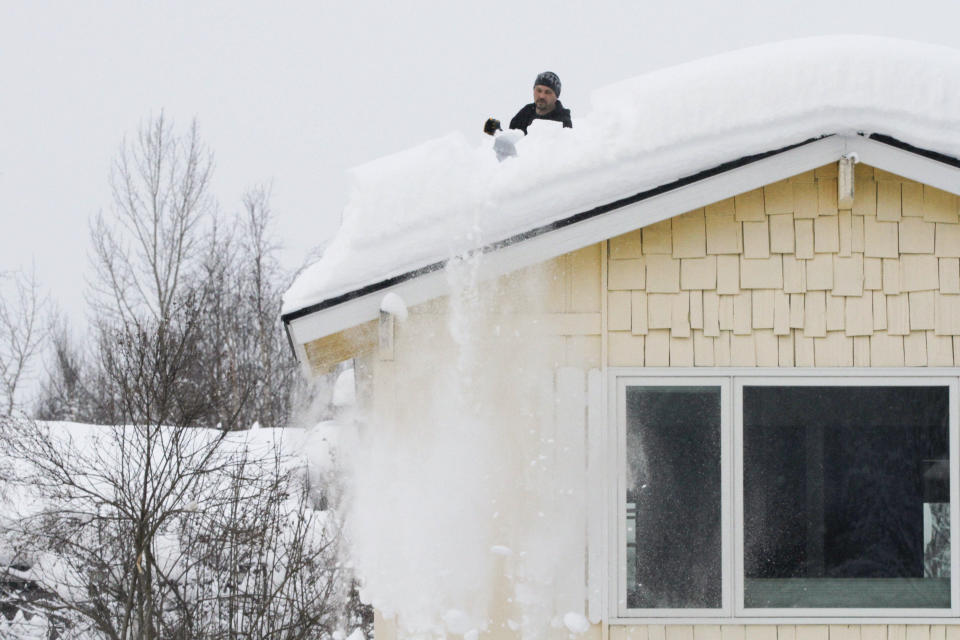 A man uses a shovel to remove snow from his roof, Monday, Jan. 29, 2024, in Anchorage, Alaska. (AP Photo/Mark Thiessen)
