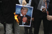 A group of protesters burn pictures of the U.S. President Donald Trump, top, and the President-elect Joe Biden in a gathering in front of Iranian Foreign Ministry on Saturday, Nov. 28, 2020, a day after the killing of Mohsen Fakhrizadeh an Iranian scientist linked to the country's nuclear program by unknown assailants near Tehran. (AP Photo/Vahid Salemi)