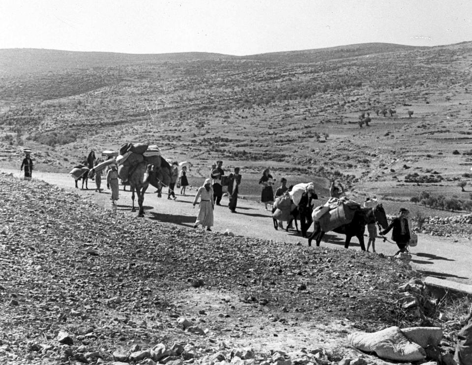 FILE - A group of Arab refugees walks along a road from Jerusalem to Lebanon, carrying their children and belongings with them on Nov. 9, 1948. The group was driven from their homes by attacks in Galilee. For the first time, the United Nations will officially commemorate the flight of hundreds of thousands of Palestinians from what is now Israel on the 75th anniversary of their exodus, an action stemming from the U.N.’s partition of British-ruled Palestine into separate Jewish and Arab states. (AP Photo/Jim Pringle, File)