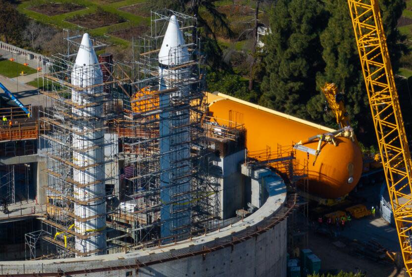 Los Angeles, CA -: The ET-94 Space Shuttle tank, right, arrives at site for installation alongside two 149-foot Solid Rocket Boosters, left, during the multi-phase Go for Stack process of creating the world's only authentic, 20-story, ready-to-launch space shuttle system display at the California Science Center's future Samuel Oschin Air and Space Center January 10. The enormous, orange ET-94 weighs 65,000 lbs., stands 154 feet top to bottom, has a diameter of 27.5 feet, and is the last remaining flight-qualified External Tank in existence. (Brian van der Brug / Los Angeles Times)