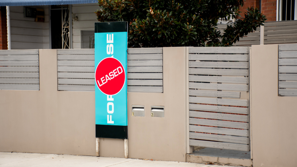 A sign in front of a property that was for rent with a 'leased' sticker to indicate it was now off the market.