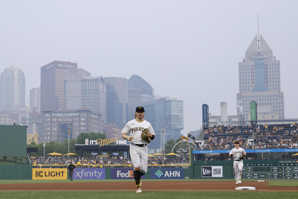 Pittsburgh Pirates center fielder Jack Suwinski (65) and right fielder Henry Davis (32) jog off the field in between innings as wildfire smoke from wildfires in Central Canada descends on the downtown skyline during an MLB game against the San Diego Padres on June 28, 2023 at PNC Park in Pittsburgh, Pennsylvania. / Credit: Joe Robbins/Icon Sportswire via Getty Images
