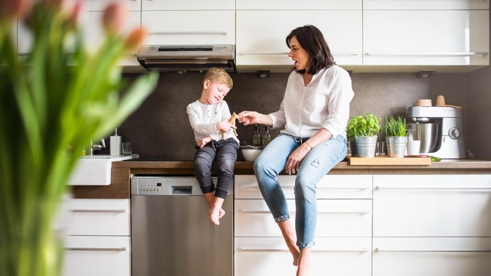 Happy senior woman with a small boy in the kitchen at home, relaxing.