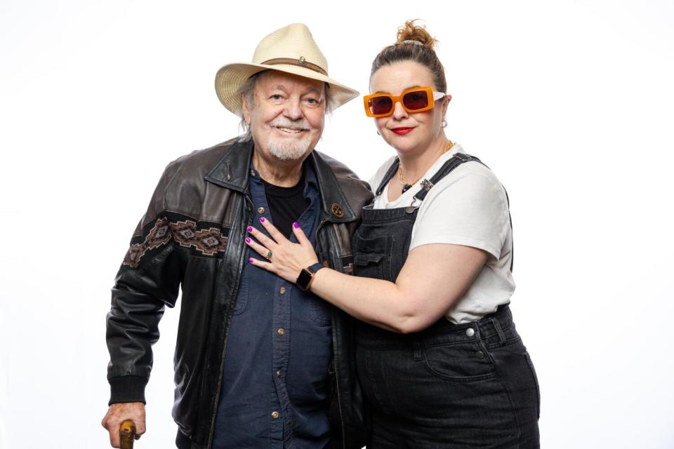 A woman puts her left hand on a man's chest as they stand together.