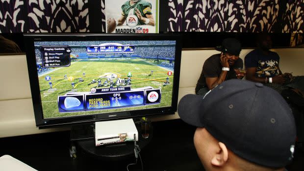 Close-up of a kid in a black baseball cap playing a video game simulating a US football match.